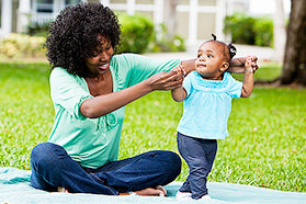 A woman helps her toddler walk.