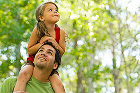 A young girl riding on her father's shoulders.